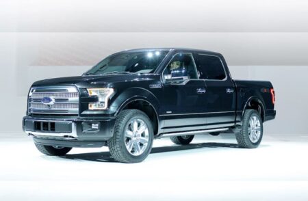 A Ford F-150 truck driving on a highway, under investigation by NHTSA for unexpected gear downshifts and rear-wheel lock-ups.