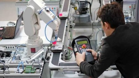 Pakistani mechatronics engineer operating an industrial robot in a smart factory – 2025