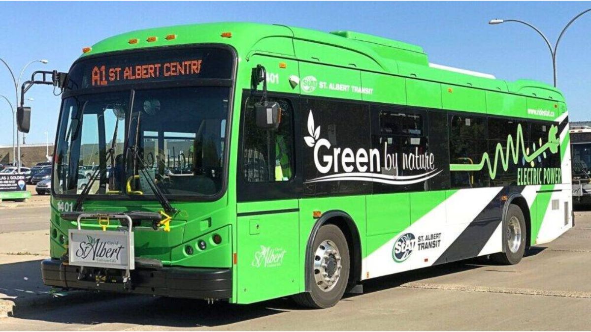 A sleek, modern electric bus with a prominent Wi-Fi symbol and "AC" visible, parked at a clean bus stop in Punjab.