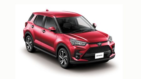 A pristine white Toyota Raize compact SUV driving on a clear road in Pakistan, showcasing its modern design and compact size.