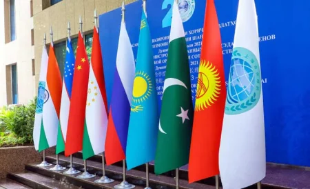 Image showing a formal meeting table with flags of SCO member nations (Pakistan, India, China prominent), emphasizing diplomatic disagreement.