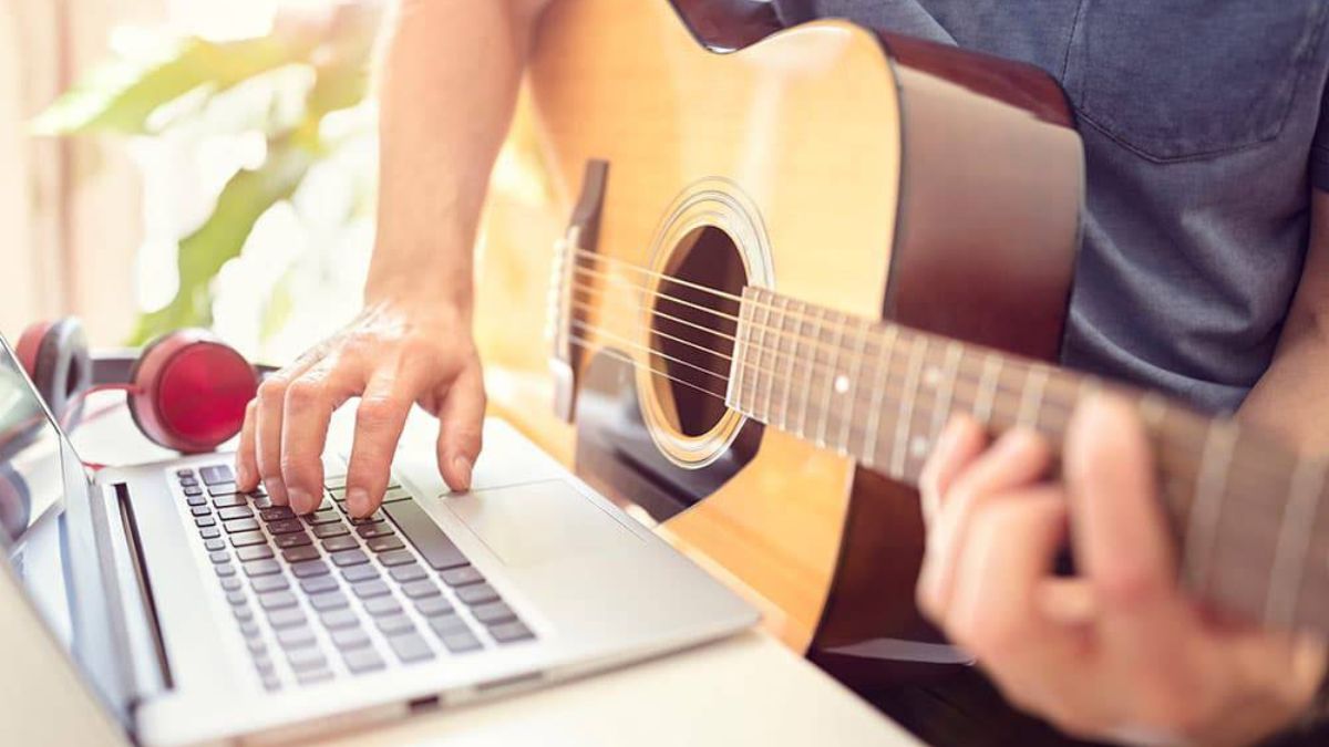 Person learning guitar online through laptop in 2025 music lesson